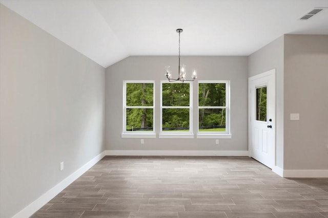unfurnished dining area featuring baseboards, wood finished floors, a chandelier, and visible vents