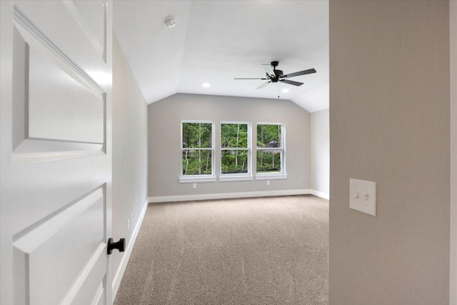 carpeted empty room featuring baseboards, a ceiling fan, and lofted ceiling