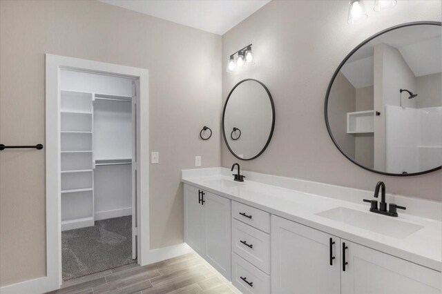 full bathroom with baseboards, a sink, wood finished floors, and a spacious closet