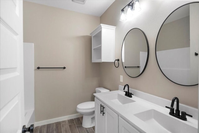 bathroom featuring a sink, baseboards, toilet, and wood finished floors