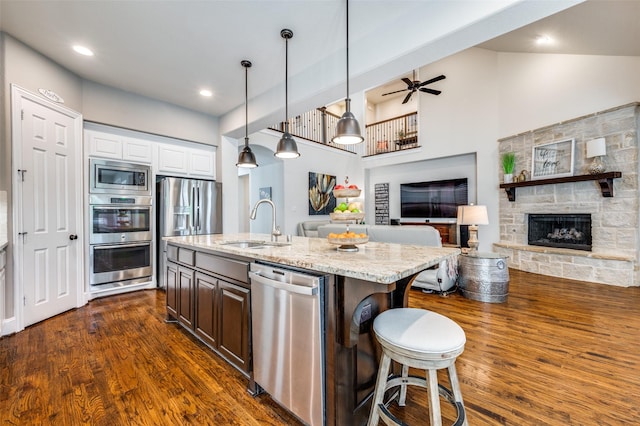 kitchen with dark wood-style flooring, stainless steel appliances, light stone counters, and a sink
