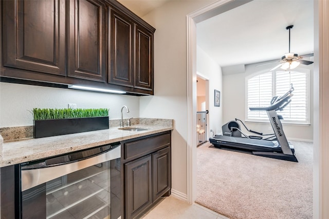 bar featuring ceiling fan, a sink, indoor wet bar, beverage cooler, and light carpet