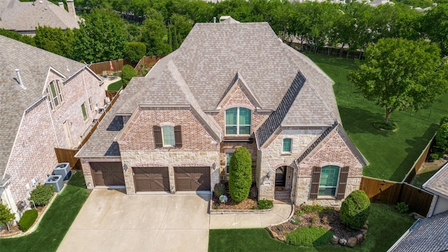 view of front of home with a shingled roof, fence, driveway, and stone siding