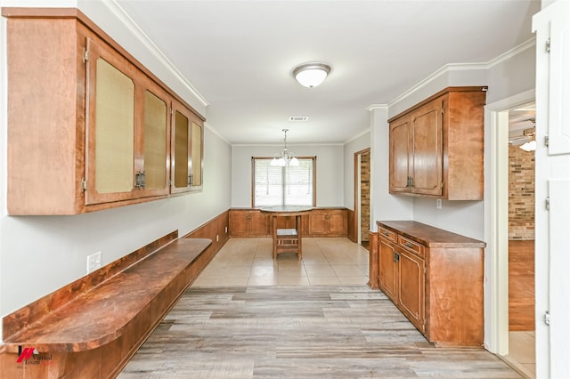 kitchen featuring dark countertops, a notable chandelier, ornamental molding, and light wood-style flooring