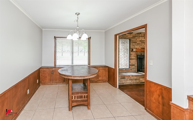 dining room featuring wooden walls, an inviting chandelier, ornamental molding, and a wainscoted wall