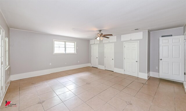 unfurnished bedroom featuring a ceiling fan, visible vents, light tile patterned floors, baseboards, and multiple closets