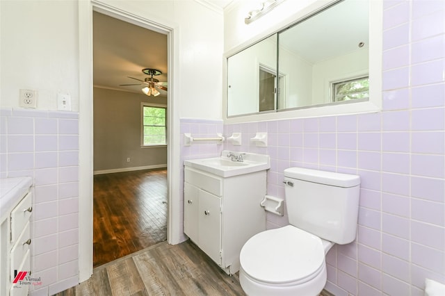 bathroom featuring ceiling fan, vanity, toilet, tile walls, and wood finished floors