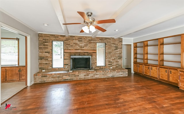unfurnished living room with a healthy amount of sunlight, beamed ceiling, a ceiling fan, and wood finished floors