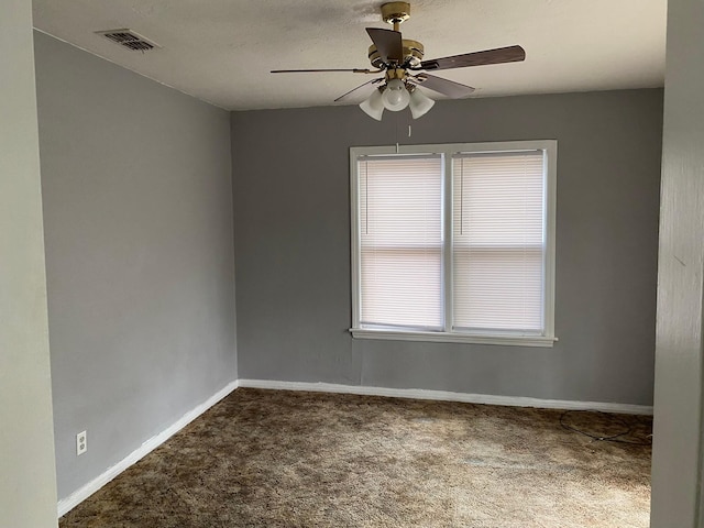 unfurnished room with baseboards, ceiling fan, dark colored carpet, and visible vents