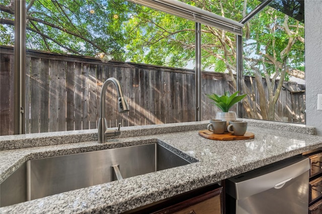 exterior details with a sink, light stone counters, and stainless steel dishwasher