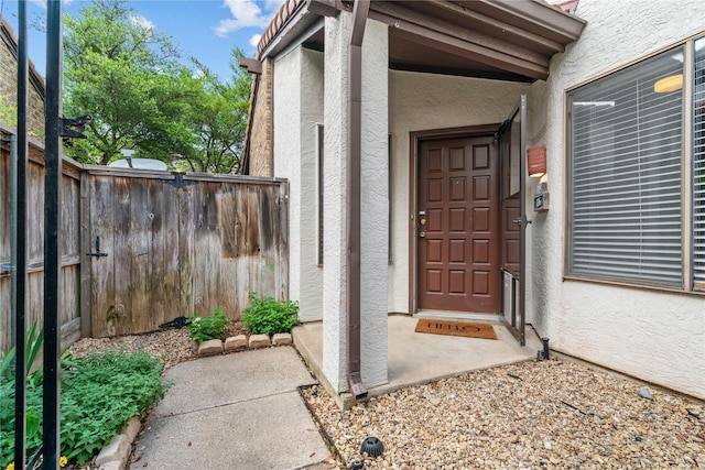 property entrance with fence and stucco siding