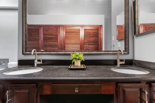 bathroom with double vanity, a sink, and toilet