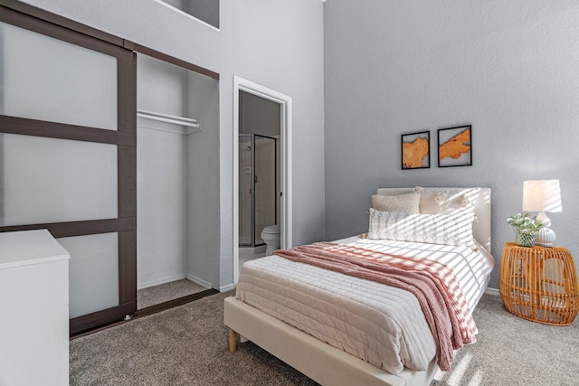 carpeted bedroom featuring baseboards, connected bathroom, and a high ceiling