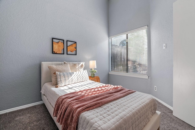 carpeted bedroom featuring baseboards and a textured wall