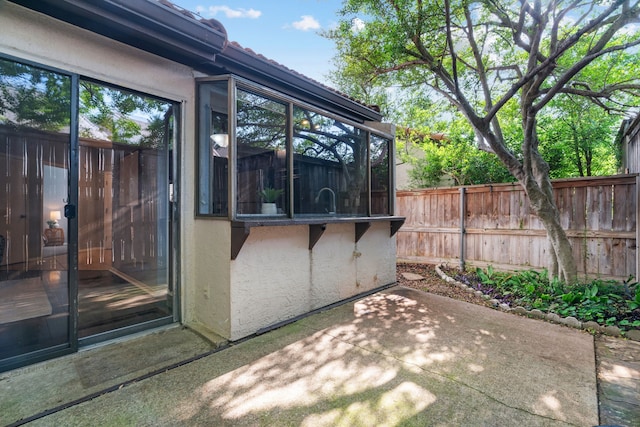 view of outdoor structure with fence and a sunroom