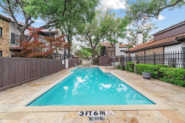 community pool with a patio area and fence