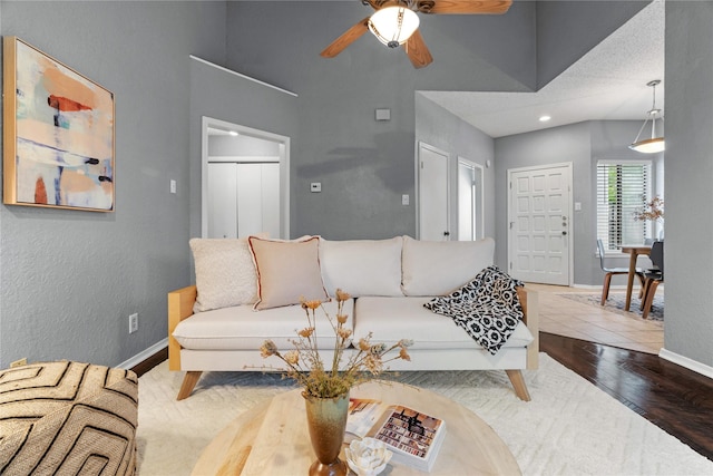 living room with a ceiling fan, wood finished floors, baseboards, a high ceiling, and recessed lighting
