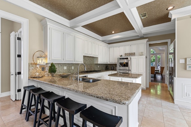 kitchen with a sink, backsplash, a peninsula, and visible vents