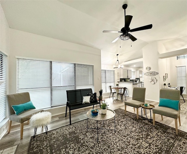 living area with baseboards, ceiling fan, wood finished floors, and lofted ceiling