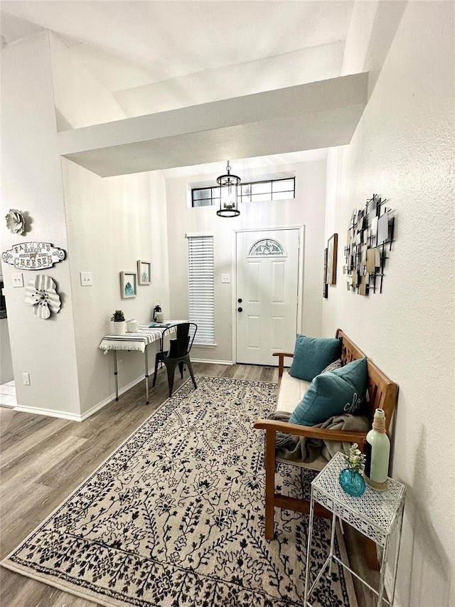 foyer entrance with baseboards, wood finished floors, and a notable chandelier