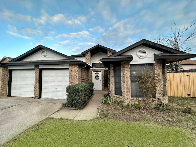 view of front facade with an attached garage, fence, brick siding, and concrete driveway
