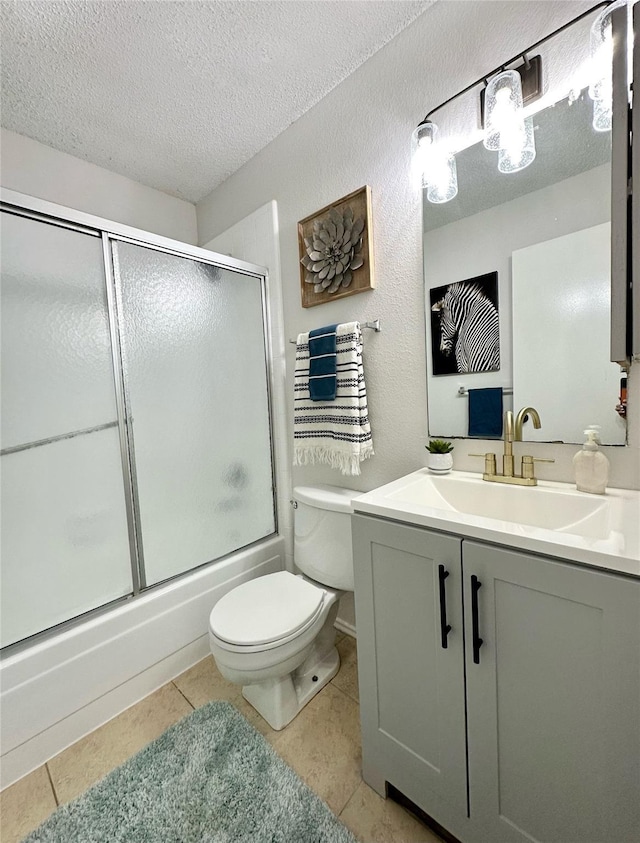 full bathroom with vanity, tile patterned flooring, toilet, bath / shower combo with glass door, and a textured ceiling