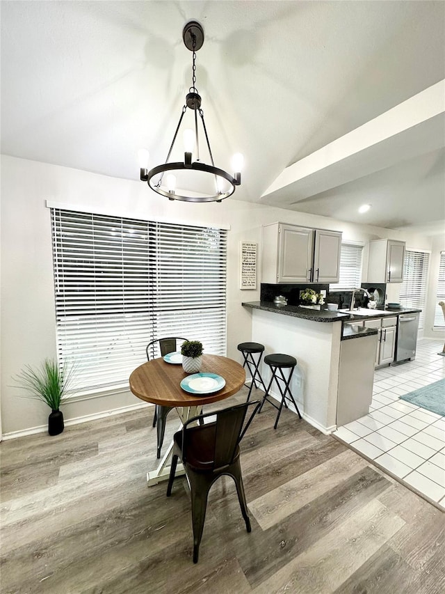 dining space featuring an inviting chandelier, baseboards, light wood-type flooring, and lofted ceiling
