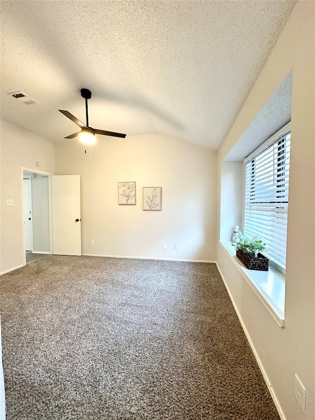 spare room with carpet flooring, ceiling fan, visible vents, a textured ceiling, and vaulted ceiling