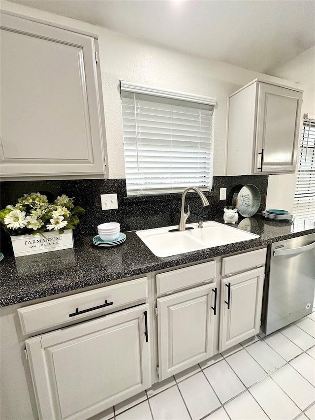 kitchen with light tile patterned flooring, a sink, dishwasher, white cabinetry, and decorative backsplash