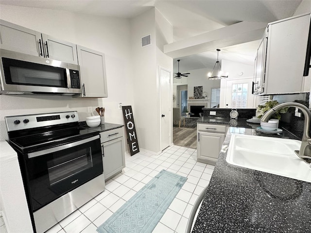kitchen with visible vents, lofted ceiling, ceiling fan with notable chandelier, a sink, and appliances with stainless steel finishes