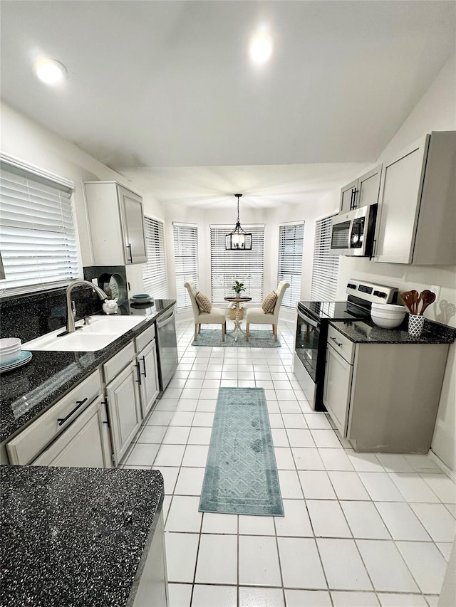 kitchen featuring a sink, appliances with stainless steel finishes, light tile patterned floors, and a wealth of natural light