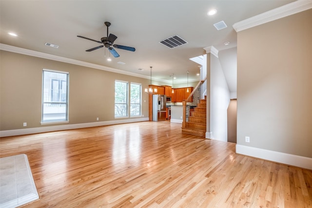 unfurnished living room with ornamental molding, ceiling fan, and visible vents
