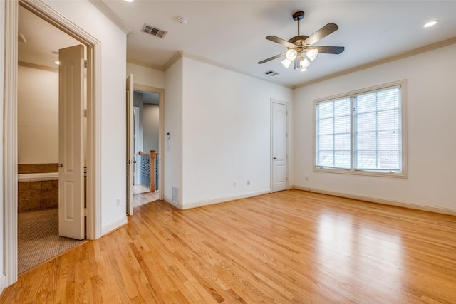 empty room featuring crown molding, a ceiling fan, visible vents, and light wood-style floors