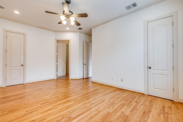 unfurnished bedroom featuring visible vents, light wood finished floors, crown molding, and baseboards