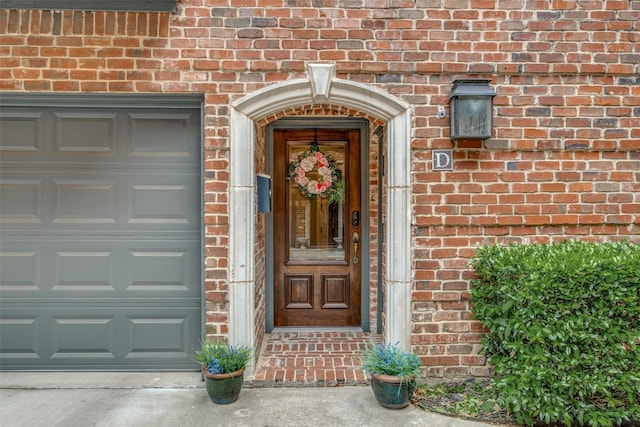 doorway to property featuring brick siding and a garage