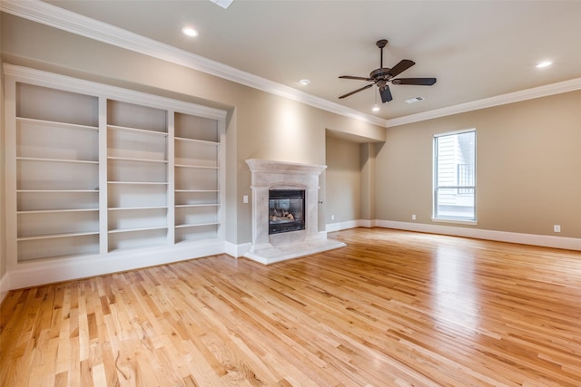 unfurnished living room with crown molding, ceiling fan, light wood-style floors, a premium fireplace, and baseboards