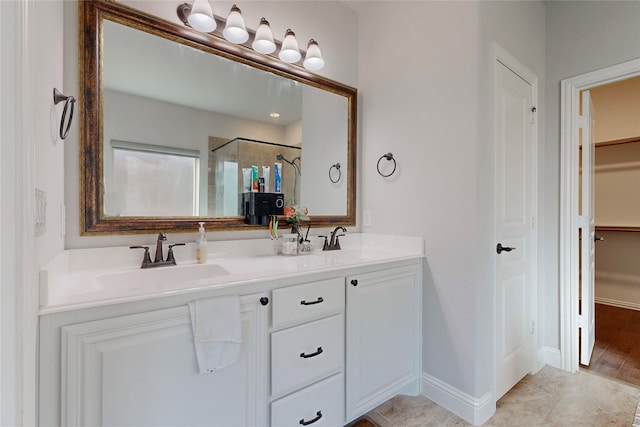 full bath with double vanity, a spacious closet, a sink, and a stall shower