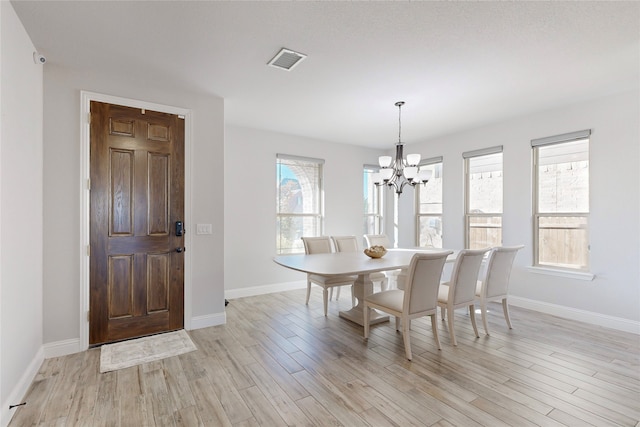 dining room with baseboards, a chandelier, light wood finished floors, and visible vents
