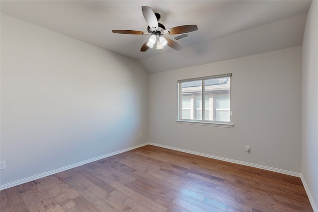 spare room with visible vents, lofted ceiling, wood finished floors, baseboards, and a ceiling fan