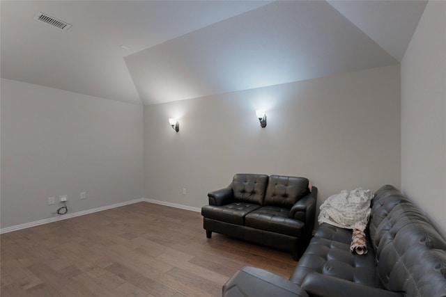living room with visible vents, baseboards, wood finished floors, and vaulted ceiling