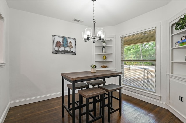 dining room with dark wood-style flooring, an inviting chandelier, built in shelves, baseboards, and visible vents