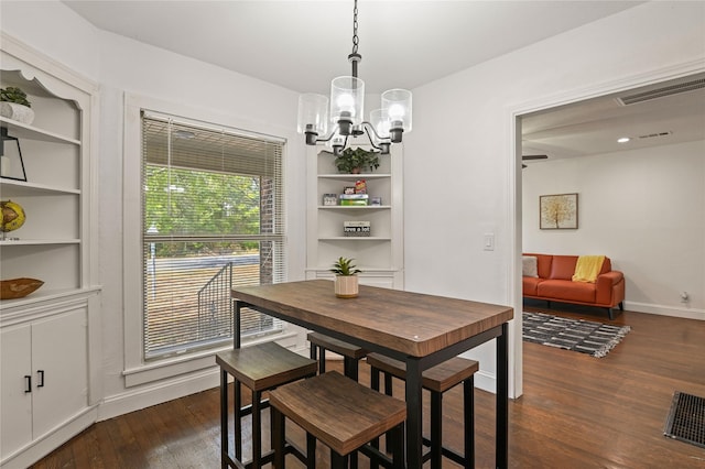 dining area with visible vents, built in features, dark wood finished floors, and a notable chandelier