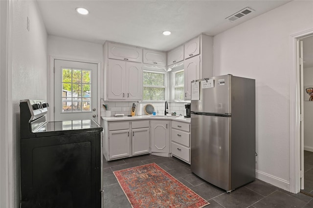 kitchen featuring freestanding refrigerator, visible vents, a healthy amount of sunlight, and washer / dryer