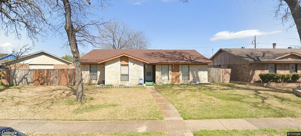 view of front of house with fence, brick siding, and a front yard
