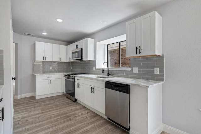 1308 Wheatfield Dr, Mesquite, TX 75149 - kitchen featuring appliances with stainless steel finishes, a sink, white cabinetry, decorative backsplash, and visible vents