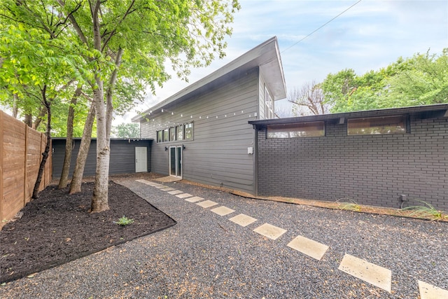 view of side of property with brick siding and fence