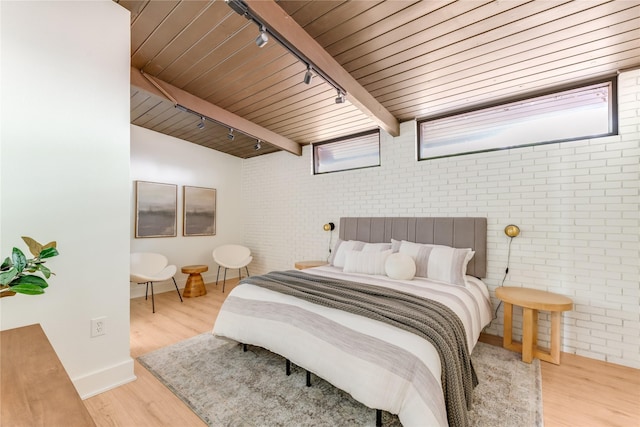 bedroom featuring track lighting, brick wall, baseboards, wood finished floors, and wood ceiling