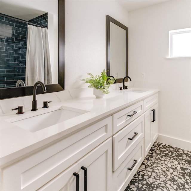 full bathroom with a sink, a shower with curtain, baseboards, and double vanity