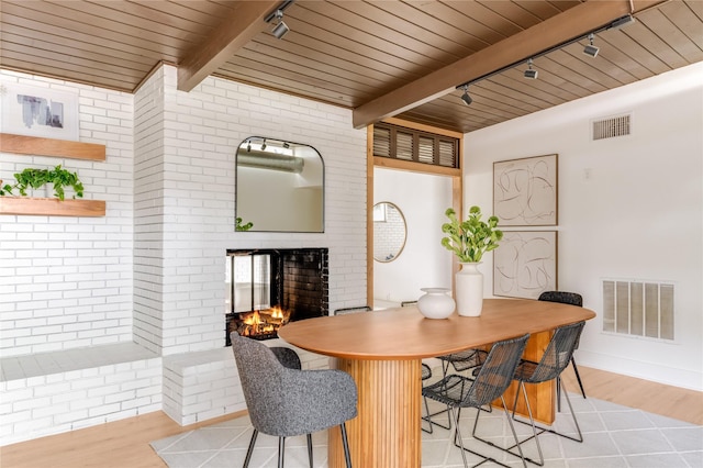 dining space with wood ceiling, a fireplace, rail lighting, and visible vents
