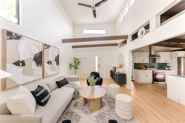 living room with ceiling fan, light wood-style flooring, and a towering ceiling